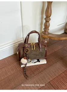 Bolso tipo almohada marrón vintage en contraste con textura de ante y estilo chic retro.