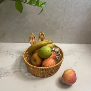 Detailed view of the cute bunny ear rattan fruit basket filled with fresh mixed fruits on marble table.