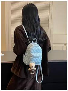 Chic mini sac à dos matelassé bleu clair pour femme avec pendentif ours, idéal pour voyages.