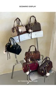 Bolso de hombro estilo almohada vintage de ante con herrajes metálicos y colgante de peluche.