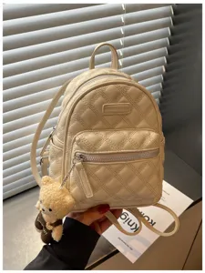 Vue détaillée d'un élégant mini sac à dos matelassé beige avec un charmant pendentif ourson.