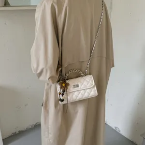Modische weiße gesteppte Schultertasche mit Kettenriemen und Perlenanhänger für Damen.