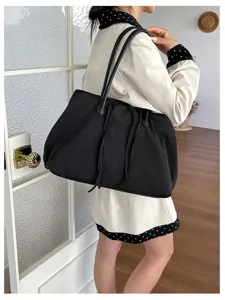 Dettaglio della borsa shopper nera casual in nylon, con spallacci e design a coulisse.