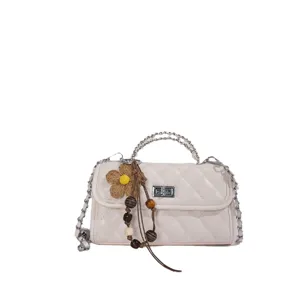 Chic quilted white shoulder bag for women with chain strap and cute flower pendant charm.
