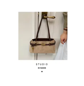 Detailed view of retro camel suede shoulder bag with brown leather straps and lock.