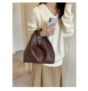Vista detallada de elegante bolso de hombro marrón oscuro con asa nudo elegante.