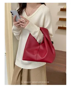 Vista detallada del bolso plisado rojo, mostrando su textura suave y elegante estilo bajo el brazo.