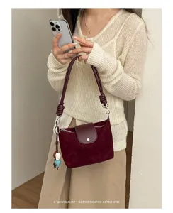 Detailed view of a retro burgundy suede shoulder bag with chic braided strap and flap closure.