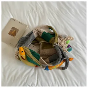 Detailed view of the casual knit tote bag featuring colorful fish ornaments on a clean white bed.
