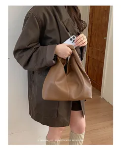 Vista detallada del elegante bolso de mano marron plisado con textura suave y gran capacidad.