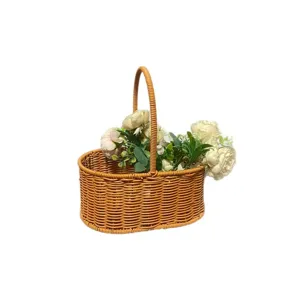 Panier de pique-nique ovale en rotin avec des fleurs pour usage en plein air et rangement.