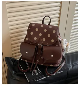 Brown polka dot backpack with front pockets and cute charm detail, casual daily commuter bag.