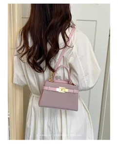 Detail shot of a retro pink shoulder bag worn by a model, featuring metallic lock and sleek design.