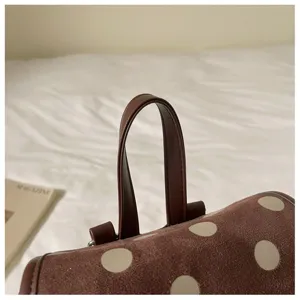 Polka dot backpack detail shot showcasing brown suede texture, leather handle and chic style.