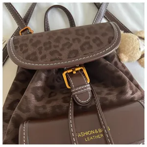 Brown leopard print backpack close-up, stylish leather design with metal buckle and stitching.