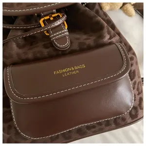 Brown leopard print backpack with dark brown leather front pocket and gold hardware details.
