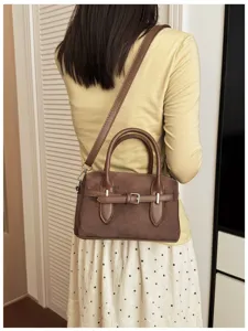Retro Boston handbag detail view, showing the elegant brown suede material and stylish belt design.