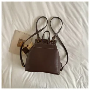 Dark brown leather casual backpack detail showing white contrast stitching and fine metal hardware.