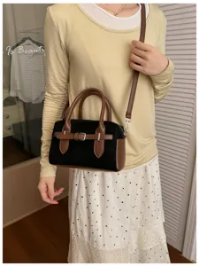 Detailed shot of retro boston handbag, black and brown contrast design with chic belt accent.