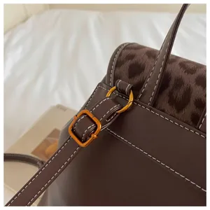 Detailed view of women casual backpack featuring brown leather, leopard print flap and metal hardware.