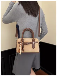Vintage suede boston handbag detail showing contrast brown leather straps and beaded charm.