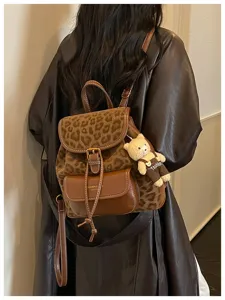 Close-up detail of stylish leopard print leather women backpack with cute bear pendant.