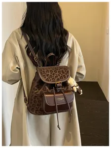 Detail view of stylish leopard print backpack with cute bear pendant and leather front pocket.