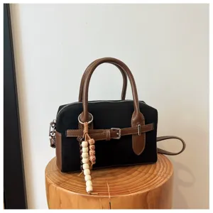 Close-up detail of vintage retro black Boston handbag with brown leather trim and wooden bead charm.