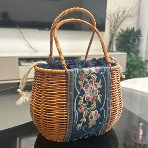 Wicker woven handbag with embroidered fabric panel, elegant oval basket for daily use.
