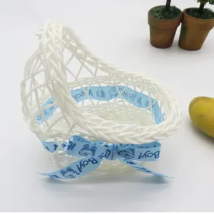 Detailed view of white plastic woven basket with blue It's A Boy ribbon for baby party decor.