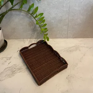 Handwoven imitation rattan storage tray detail, dark brown bread fruit basket with wavy rim.