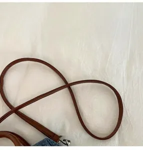 Detail shot of the brown leather shoulder strap showing fine texture and durable metal hardware.