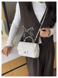 Primo piano dettagliato di una borsa a tracolla trapuntata bianca con catena e chiusura.