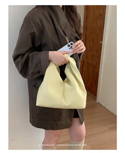 Vista detallada de un elegante bolso hobo amarillo plisado de cuero, diseño minimalista.