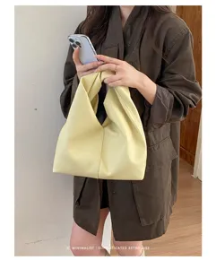 Vista detallada del bolso hobo holgado amarillo, textura de cuero suave, diseño minimalista.