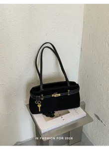 Detailed view of black suede shoulder bag with metal lock charm, chic daily fashion tote style.