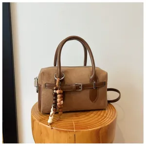 Detail view of retro brown suede Boston handbag with chic wooden bead pendant and handles.