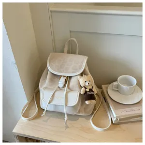 Detail view of a chic beige mini backpack with leopard print flap and cute bear pendant.