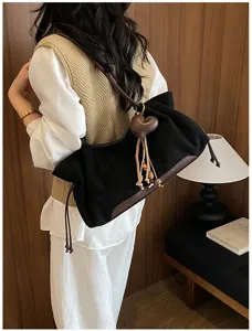 Close-up detail of vintage style black shoulder hobo bag with brown leather strap and heart tassel.