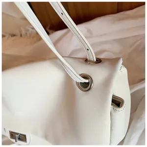 Vista dettagliata della borsa a spalla bianca minimalista con occhielli e chiusura.