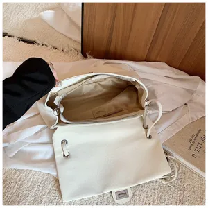 Borsa a tracolla intrecciata bianca dettaglio, con design a patta e ampio spazio.