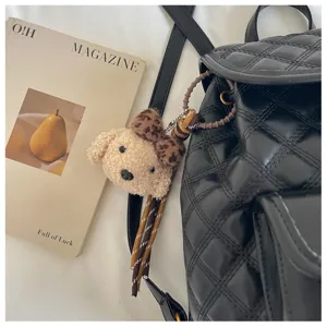 Classic black quilted backpack with stylish plush keychain, perfect for daily casual commuting.