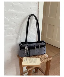 Detailopname van vintage grijze schoudertas met polkadots, zwarte riemgesp en parelhangertje.