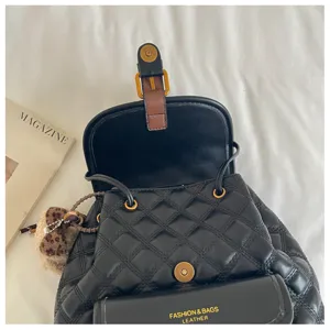 Close-up detail of black quilted leather backpack featuring metal hardware and front pocket.