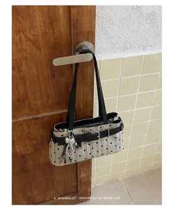 Gedetailleerd overzicht van retro polkadot schoudertas met zwarte gesp en strikhanger.