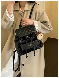 Stylish black quilted leather vintage backpack with front pocket and cute bear charm.