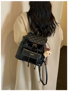 Chic black quilted leather backpack for women, stylish casual travel daypack with cute bear pendant.