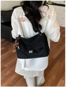 Vista dettagliata della borsa a spalla da donna nera in pelle intrecciata con chiusura e ciondolo.