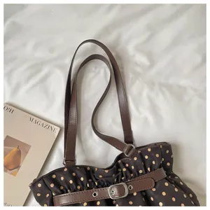 Detalle del bolso de hombro plisado con lunares marrones, hebilla de cinturón y asas dobles