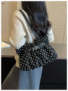 Vista de detalle que muestra el bolso de hombro fruncido de lunares con elegante hebilla.